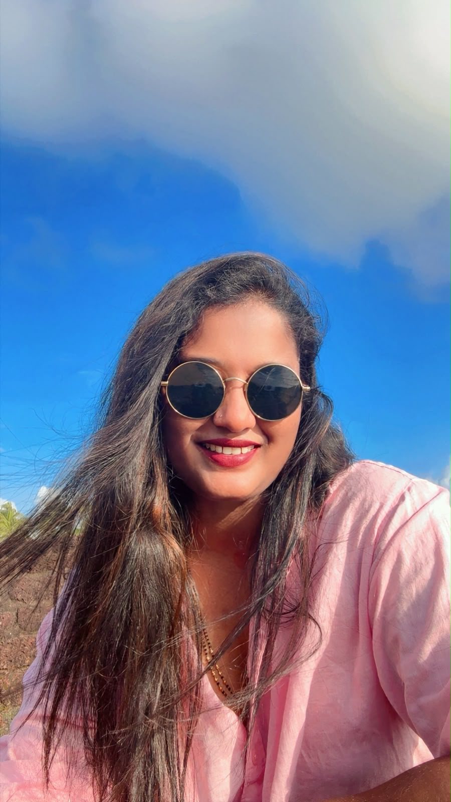 Kalpana Naik smiling under a bright blue sky